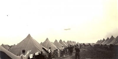 An observation blimp flying past a large army camp